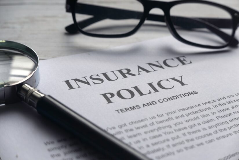 Insurance Policy paper with pair of glasses and magnifying glass